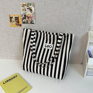 Detail of blue and white striped canvas tote bag with Leo logo on a desktop scene