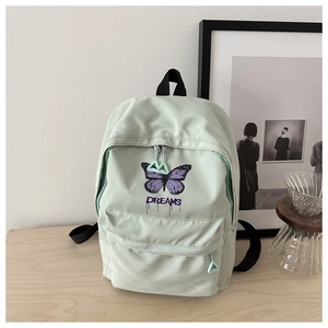 Detail von mintgrünem Schulrucksack mit lila Schmetterling und DREAMS Text auf dem Tisch