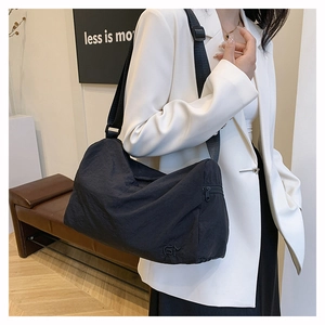 Détail du sac fourre-tout en nylon noir montrant la bandoulière large et le tissu texturé