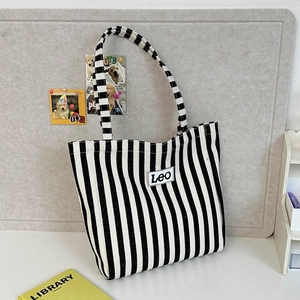 Detailed view of striped canvas tote bag featuring black and white vertical patterns and Leo label
