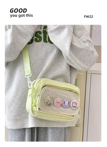 Detail view of light green canvas crossbody bag with transparent mesh pocket and bunny badges