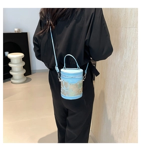 Detailed view of light blue bucket bag with vintage gold patterns and silver metal hooks