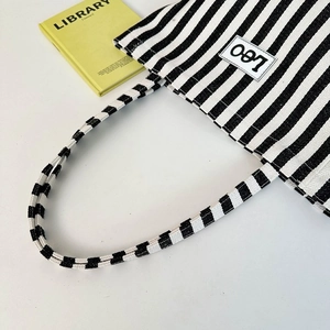 Detail of blue and white striped canvas tote bag with Leo logo on minimalist white background