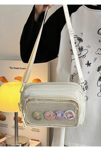 Detail of a creamy white nylon crossbody bag featuring transparent mesh pocket and badges