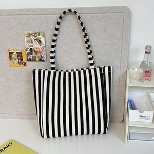 Detailed view of the black and white striped canvas tote bag on a desk background