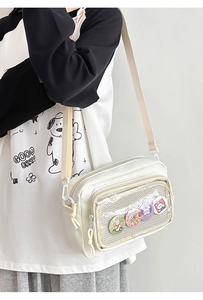 Detailed view of white nylon crossbody bag with transparent mesh pocket and cartoon badges