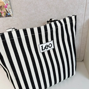 Detail of black and white striped canvas tote bag with Leo letter patch and twill texture