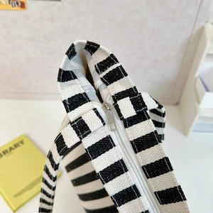 Detailed close-up of smooth silver metal zipper and stitching on striped canvas tote bag