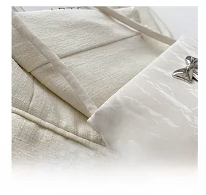 Dettaglio borsa in pelle bianca motivo marmo con fibbia decorativa a fiocco argento