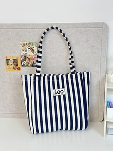 Close-up of blue and white striped canvas tote bag with LEO logo label on gray background