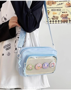 Detail of light blue crossbody ita bag with clear window and cute rabbit badges