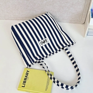 Detail of blue and white striped canvas tote bag featuring a white leo brand label