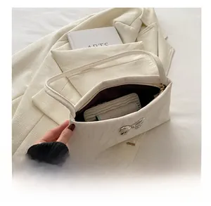 Interno spazioso della borsa beige con fiocco che mostra la capacità per telefono e carte