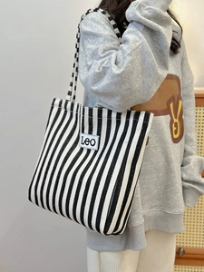 Detail of blue and white striped canvas tote bag with LEO patch and sturdy shoulder straps