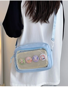Detail view of light blue transparent ita bag with cute bunny badges and mesh interior