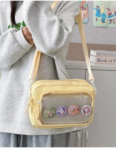 Detail of light yellow canvas Ita bag with transparent pocket and four cute bunny badges