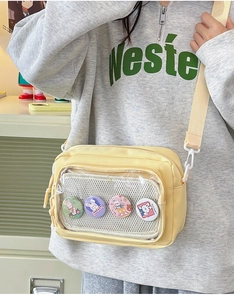 Detail view of yellow canvas crossbody bag featuring clear window and cute bunny badges