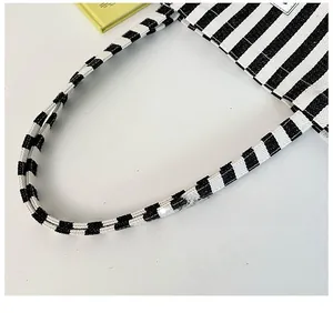 Detail of reinforced woven handles on a striped canvas tote bag with clean stitching