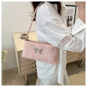 Dettaglio della borsa sottobraccio rosa plissettata con fiocco in metallo argento e tracolla