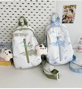 Detalle de bolsos bandolera con estampado de tinta, llavero de panda y cremallera triangular