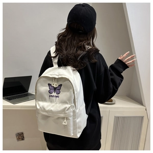 Detail eines weißen Rucksacks mit lila Schmetterlingsstickerei und Dreams-Schriftzug