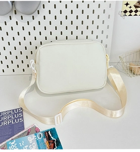 Close-up of a minimalist cream-colored canvas crossbody bag with adjustable strap and buckle