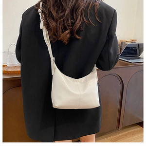 Schicke cremefarbene Leder-Hobo-Tasche an Model mit schwarzem Blazer im gemütlichen Büro