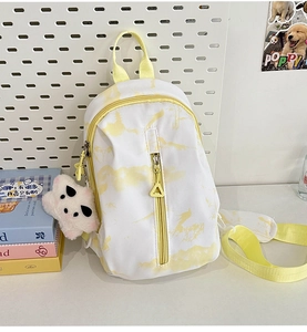 Detalle de mini bolso de pecho tie-dye amarillo con amuleto de panda en tablero blanco