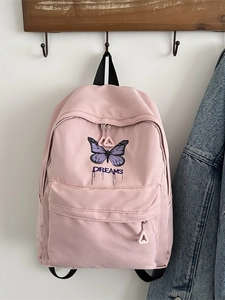 Rosa Schulrucksack mit lila Schmetterlingsdruck und Dreams-Schriftzug am Haken hängend