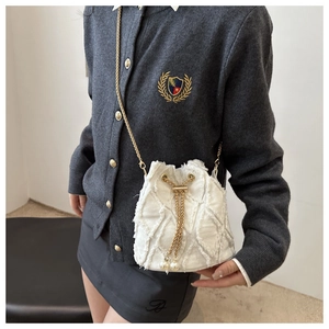 Dettaglio borsa a secchiello in denim bianco con coulisse di perle e catena d'oro