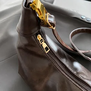 Close-up of smooth gold zipper and metallic buckle on dark brown leather handbag