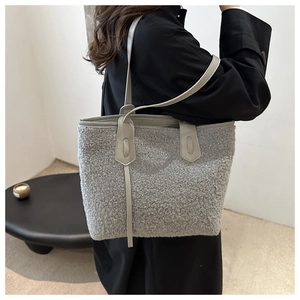 Dettaglio della borsa tote in ecopelliccia grigio chiaro con un lungo cappotto nero