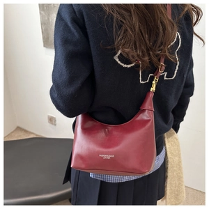 Model wearing dark red leather hobo bag with adjustable strap and gold hardware
