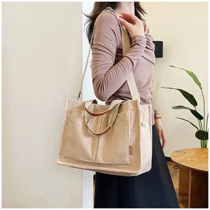 Detail of beige corduroy tote bag showing side pocket with Fashion label and leather handle