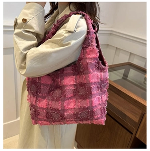 Detailaufnahme einer rosa Tweed-Tote-Bag mit Fransentextur auf beige Trenchcoat