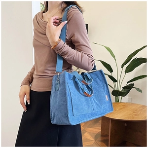 Detail of blue corduroy tote bag showing thick texture, fashion tag and adjustable strap