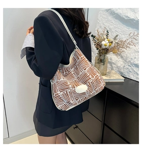 Hobo bag featuring a brown and white woven pattern with elegant white trim on a model
