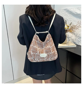 Detail of geometric pattern tote bag with leather strap shown in use by a model
