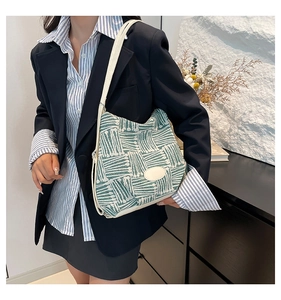 Detail view of woven tweed crossbody bag with adjustable strap on a navy blazer