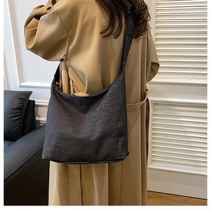 Détail du grand sac cabas noir en toile avec bandoulière porté avec un trench-coat