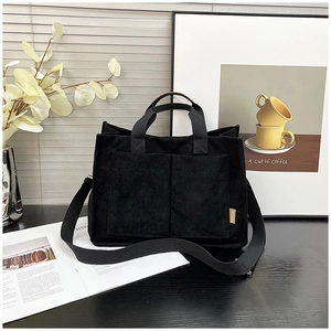 Detailed texture of black corduroy tote bag with dual handles and side fashion label