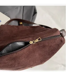 Primer plano de la cremallera dorada suave y ante marrón oscuro del bolso de mensajero