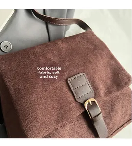 Vista detallada del bolso mensajero de ante suave que muestra la textura y hebilla