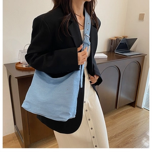 Détail de la large bandoulière réglable avec boucles argentées sur sac cabas en jean bleu