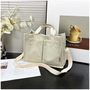 Detail view of beige corduroy tote bag showing front pockets and adjustable strap