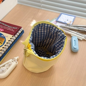 Close-up of yellow canvas pencil bag featuring a blue and white checkered inner lining