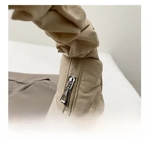 Detailed close-up of the smooth silver zipper and pleated texture on the apricot cloud bag