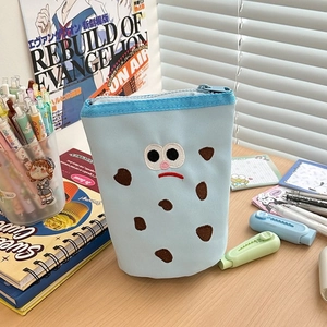 Detail view of light blue canvas pencil case with cute embroidery on a desk