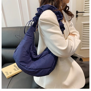 Detail of deep blue quilted dumpling bag with stylish ruched cloud shoulder strap