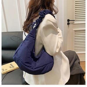 Detail of dark blue quilted crescent bag with drawstring and ruched shoulder strap